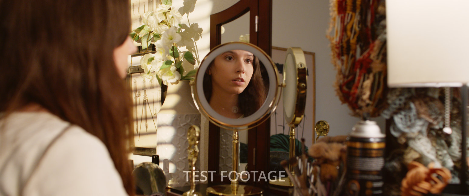 Ava getting ready in her room, looking into a mirror as she does her makeup
